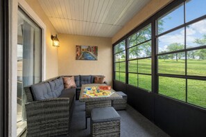 A cozy corner with a sectional sofa, a small table, and a large window offering a view of a grassy field. - Modern Spacious Condo with no step access, pools, fishing, games and golf! (Branson)