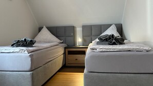 Ein Doppelzimmer mit zwei Betten, einem Nachttisch, einer Lampe und Holzboden.
