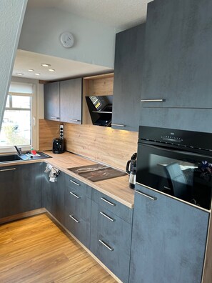 A modern kitchen with a built-in oven, a coffee maker, and a window above the sink. - Star of the Island (Borkum)