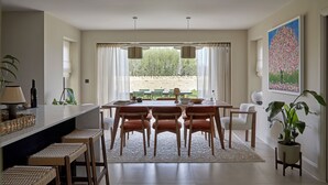 A spacious dining area with a large table, multiple chairs, and a view of a fenced outdoor area.