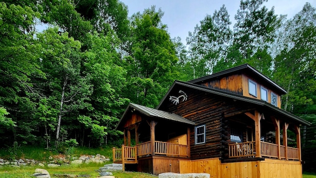 Une cabane en bois dotée d’un porche et d’un chemin de pierre menant à l’entrée.