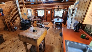 L’intérieur d’un chalet rustique comprend un coin repas, une cuisine et un escalier menant à une mezzanine.