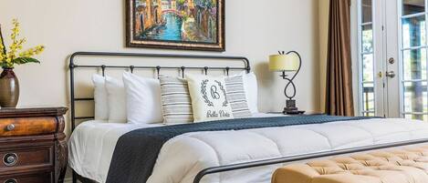 A neatly arranged bedroom with a bed, bedside table, lamp, and a painting on the wall.