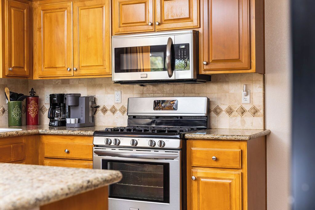 A kitchen with wooden cabinets, a stainless steel microwave, a coffee maker, and a stove.