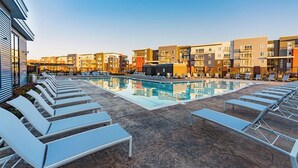 Poolområde på taget med liggestole og udsigt til høje bygninger.