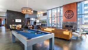 Et moderne poolområde indendørs med poolbord, siddepladser og pejs.