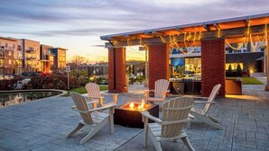En udendørs terrasse med Adirondack-stole og en bålplads.