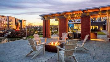 Une terrasse extérieure avec des fauteuils Adirondack et un foyer.