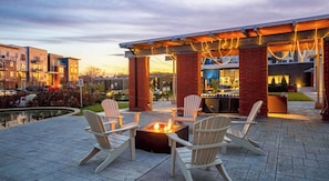 An outdoor patio with Adirondack chairs and a fire pit.