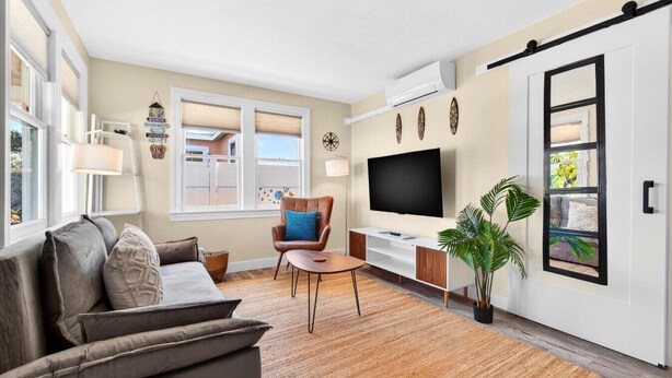 Een moderne woonkamer met een bank, salontafel, televisie en een schuifdeur.
