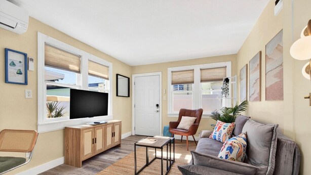 A living room with a sofa, armchair, TV, wooden cabinet, and a small table. - Covare Suite 4 (St. Pete Beach)