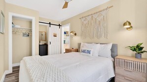 A bedroom with a bed, bedside table, wall decor, and a ceiling fan. - Covare Suite 4 (St. Pete Beach)