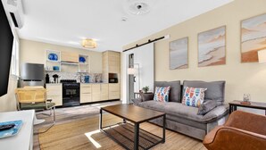 En moderne stue med sofa, sofabord og spiseområde med bord og stole.