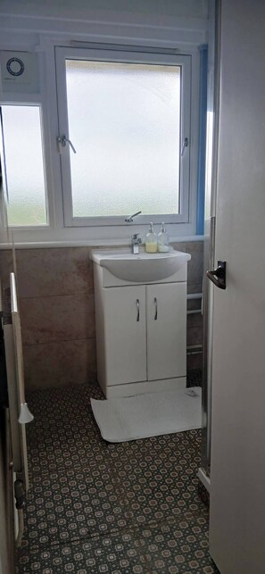 A bathroom with a window, a sink, and patterned floor tiles. - Cozy 2-bedroom Apartment in Central London (London)