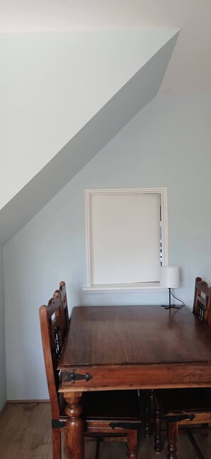 A dining room with a wooden table and chairs, a window with blinds, and a table lamp. - Cozy 2-bedroom Apartment in Central London (London)