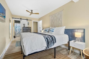 Un dormitorio con cama, mesita de noche, lámpara y ventilador de techo.
