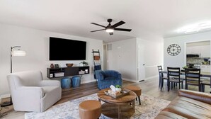 Un salon moderne comprenant un canapé, un fauteuil, une table basse et un téléviseur.
