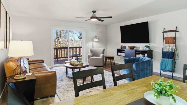 Un salon comprenant un canapé, des fauteuils, une table à manger, un téléviseur et un ventilateur de plafond.