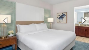 Hotelkamer met een bed, nachtkastjes, een plafondventilator, een schilderij aan de muur en uitzicht op de badkamer.