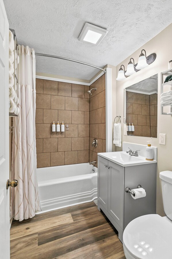Un baño con bañera, ducha, tocador con espejo y retrete.