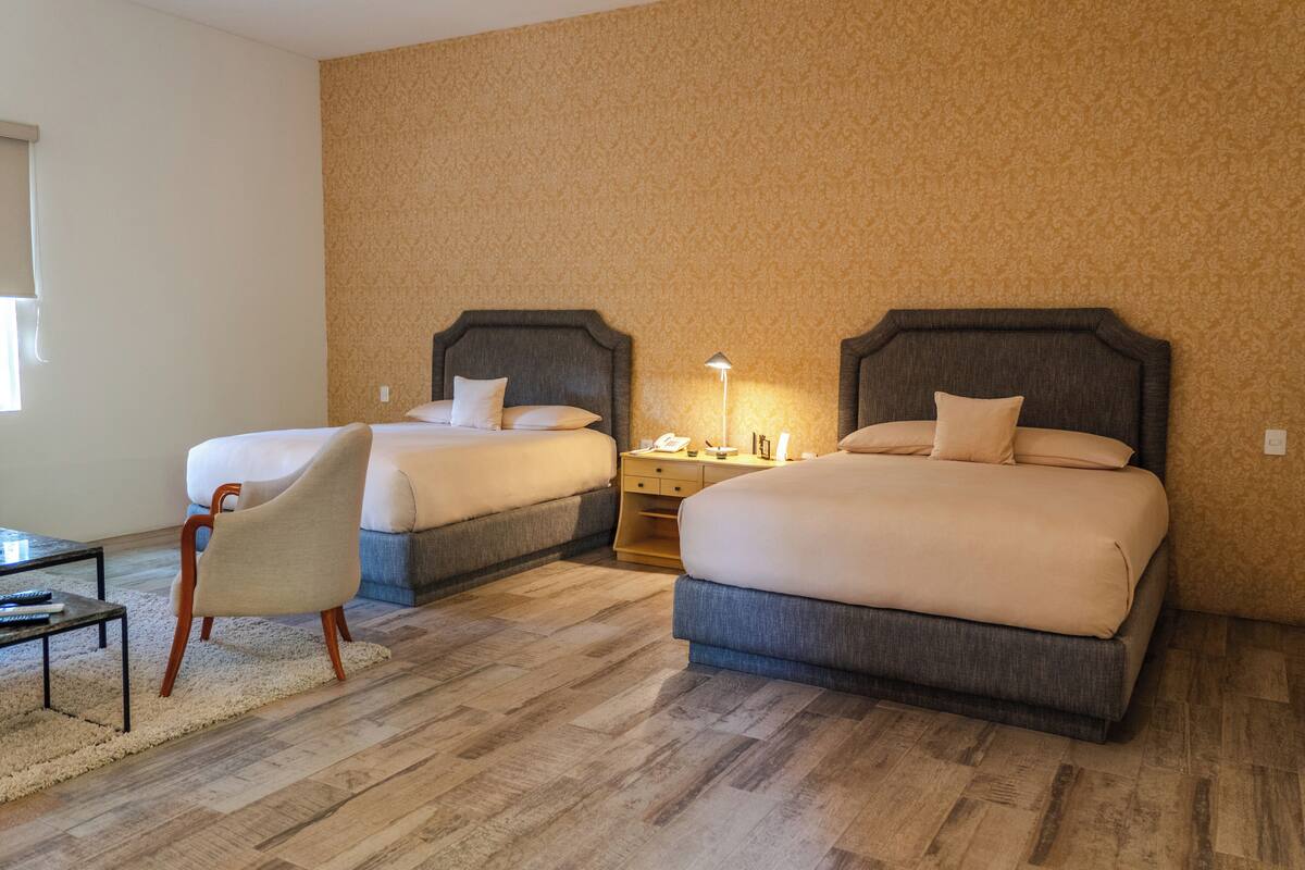 Een hotelkamer met twee bedden, een nachtkastje, een stoel en een kleine tafel.