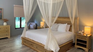 Ein Schlafzimmer mit Himmelbett, Nachttischen mit Lampen und einem Beistelltischchen mit Telefon.