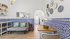 Ein gemütliches Zimmer mit einer Couch, einem Tisch und einer mit Tellern dekorierten Wand.