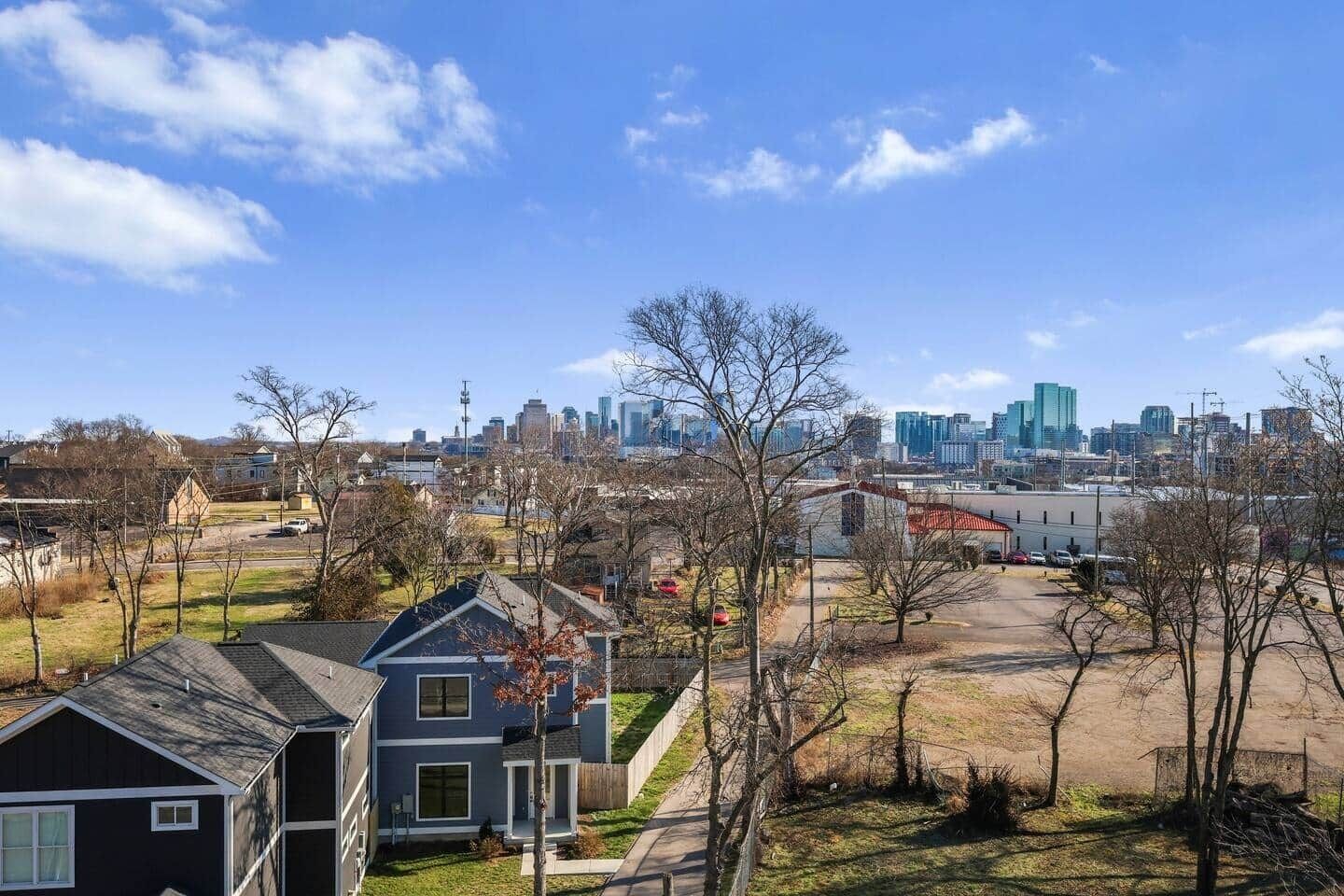 A residential area with houses, a parking lot, and a city skyline in the background.