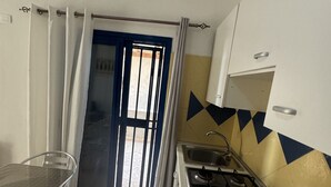 Eine kompakte Küche mit Gasherd, Spüle und einem Essbereich mit einem Metalltisch und Stühlen.