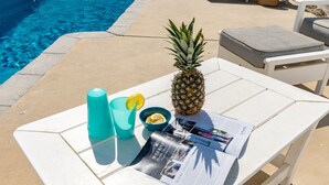 A white table with a pineapple, a magazine, a blue cup, and a lemon wedge. - Sunny Bungalow Retreat w/Pool + 6 Person Golf Cart Included (Emerald Isle)