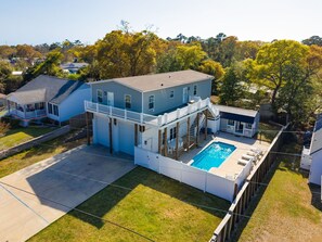 A two-story house with a pool, a covered patio, and a fenced yard.
