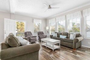 A living room with a ceiling fan, two armchairs, a sofa, and a coffee table.