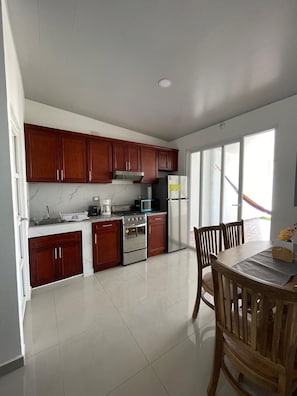 Una cocina moderna con armarios de madera, electrodomésticos de acero inoxidable y un comedor con mesa y sillas.