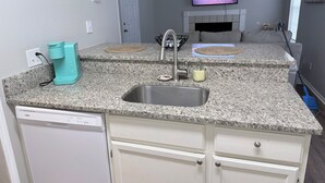 A kitchen with granite countertops, a stainless steel sink, a coffee maker, and a dishwasher. - Cozy Beachy Riverwalk Condo – Close to Downtown & Beaches (Pensacola)