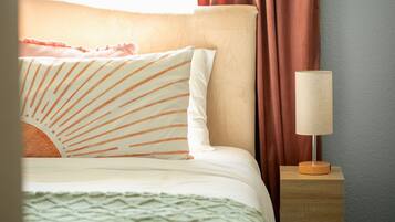 A neatly made bed with striped pillows, a bedside lamp, and a wooden nightstand.