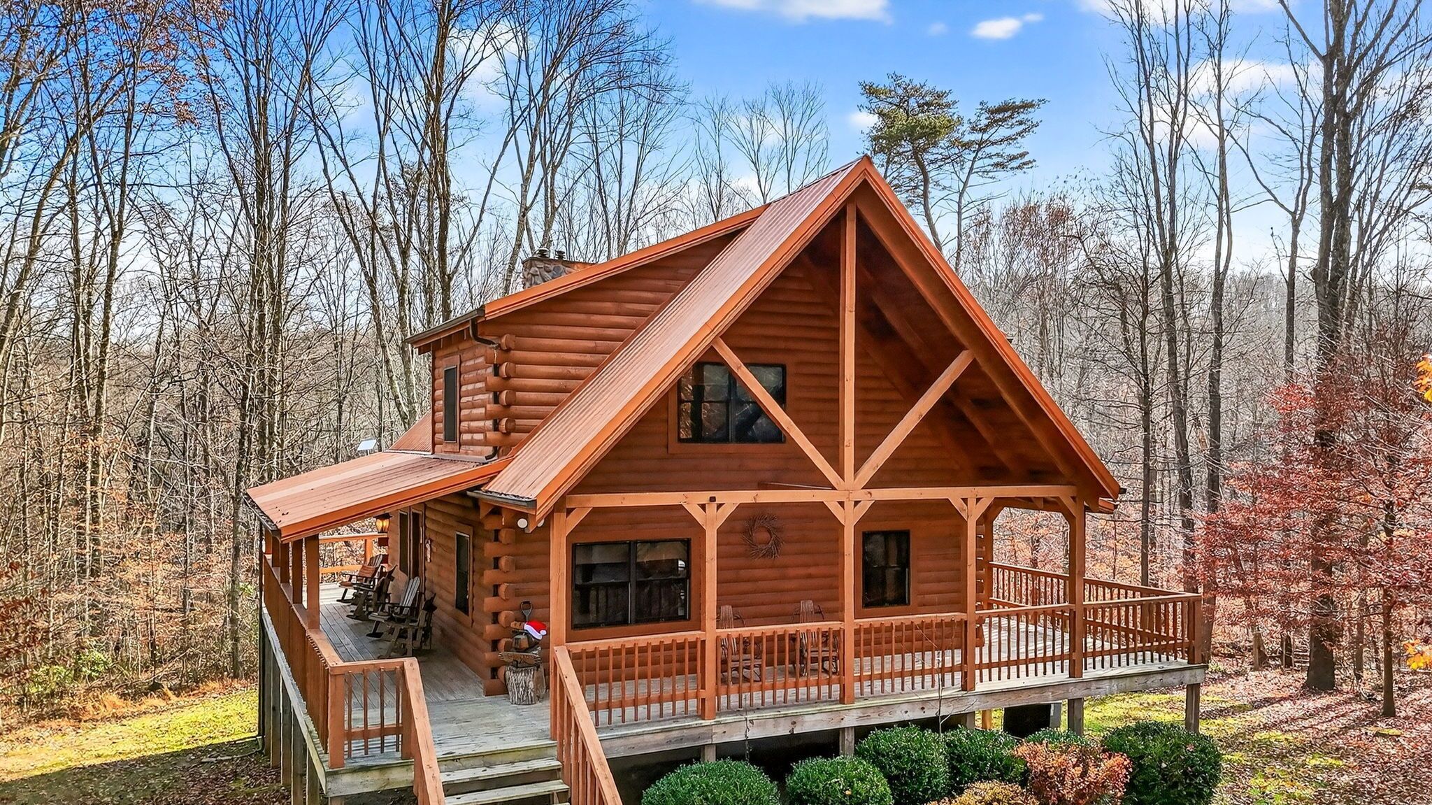 A log cabin with a porch, multiple windows, and a chimney.