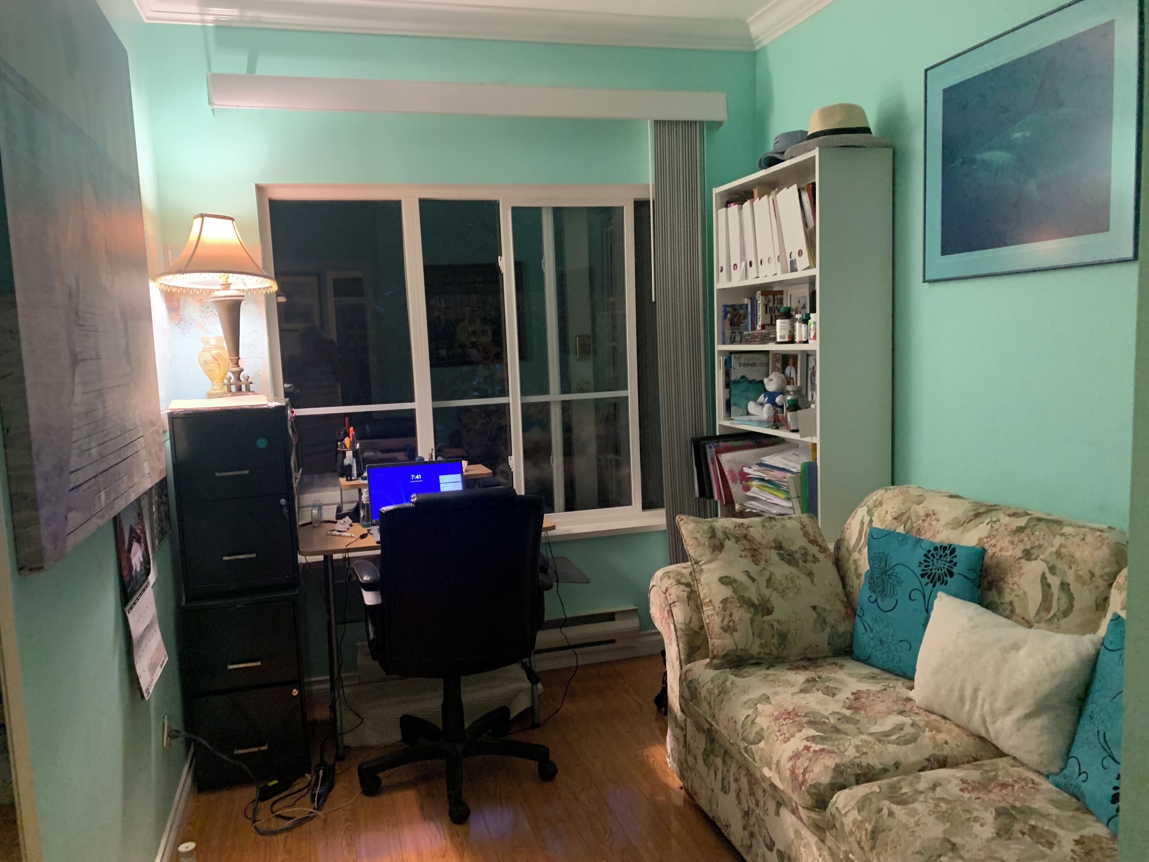 A room with a desk, computer, chair, and a couch.