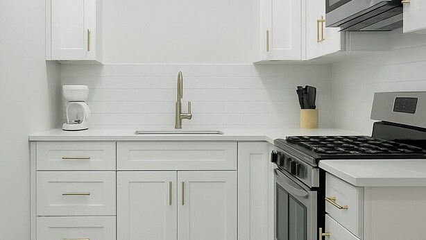 A modern kitchen with white cabinetry, a stainless steel stove, and a herringbone-patterned floor.