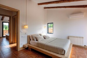 Un dormitorio con estructura de cama de madera, una ventana, un equipo de aire acondicionado y un radiador.