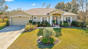 A two-story house with a garage, a front porch, and a well-maintained lawn.