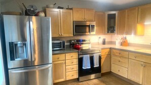 A modern kitchen with stainless steel appliances, wooden cabinets, and a tiled backsplash.