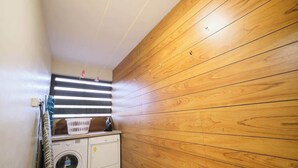 Een wasserette met een wasmachine, droger en houten wand.
