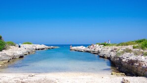 Paesaggio costiero con rocce e acqua cristallina blu.