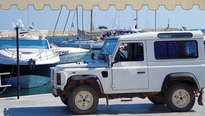 Un veicolo fuoristrada bianco parcheggiato in una marina, con diverse barche.