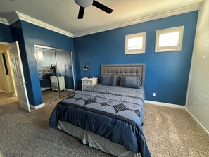 A bedroom with a bed, nightstands, a mirror, and a ceiling fan. - Dream rental home (North Las Vegas)