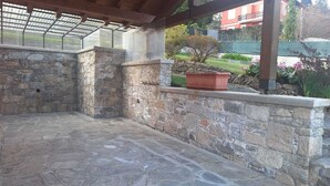A stone-walled patio with a potted plant and a view of a residential area. - Small Villa "The Palm" (Colazza)