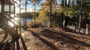 A wooden deck with a view of a lake and trees. - Deep water, private dock, beautiful sunsets, fishing, kayaking or boating. (Gainesville)
