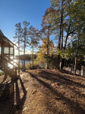 A wooden deck with a view of a lake and trees. - Deep water, private dock, beautiful sunsets, fishing, kayaking or boating. (Gainesville)