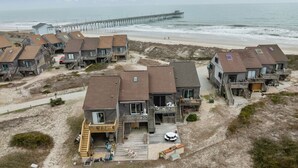 Ein Ferienhaus am Meer mit mehreren Holzhäusern, einer Steg und einem Sandstrand.