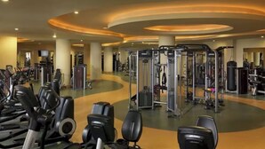 Ein Fitnessstudio mit verschiedenen Trainingsgeräten, darunter Laufbändern und Gewichten.